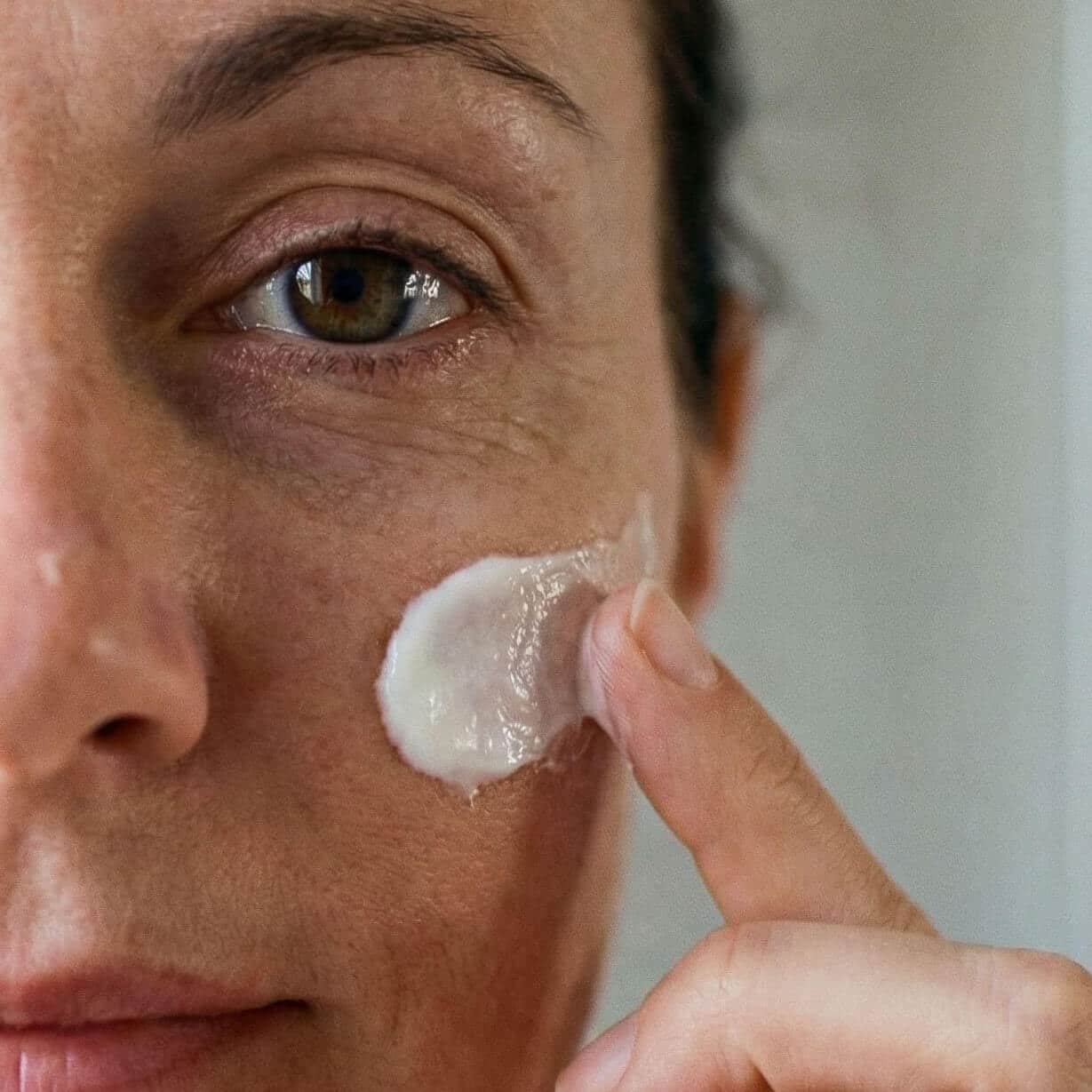 Application d’une crème visage au lait de chèvre sur la joue lors de la routine quotidienne