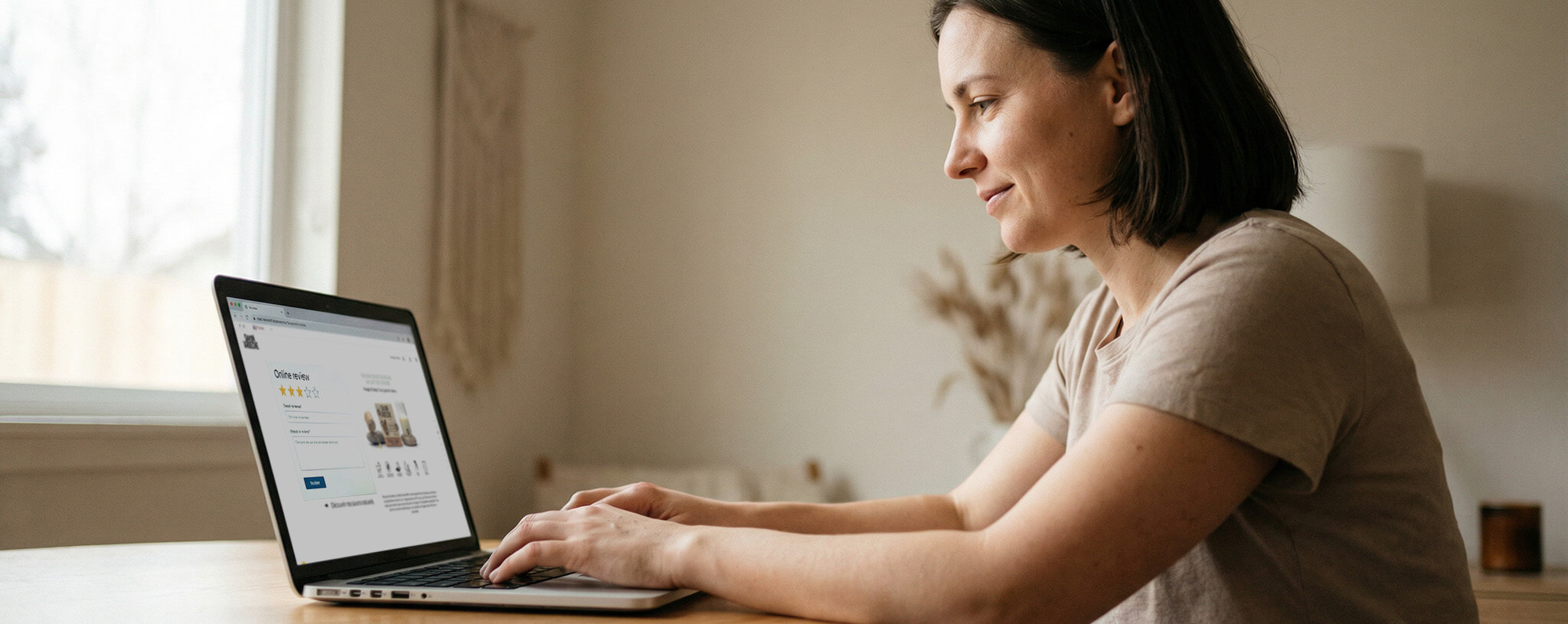 Jeune femme rédigeant un avis client en ligne pour un produit de soin au lait de chèvre, depuis son domicile