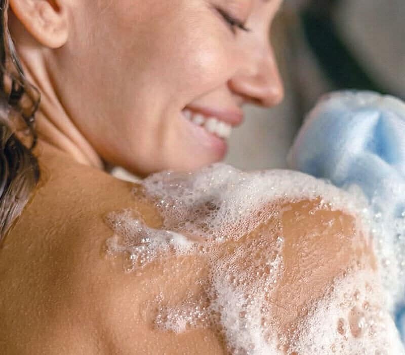 Application d’un gel douche artisanal produisant une mousse fine avec une fleur de douche