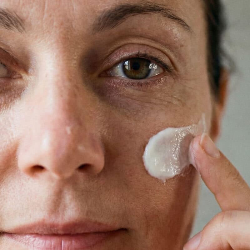 Gros plan sur la texture d’une crème visage au lait de chèvre appliquée sur une peau mature