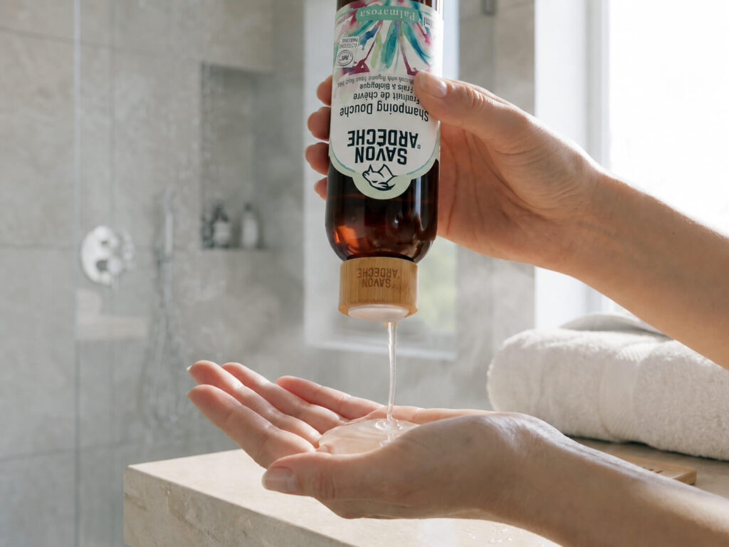 Shampoing douche Palmarosa Savon d'Ardèche versé dans la main avec son bouchon Disc Top